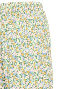 Jupe taille haute avec une ceinture élastique, présentant un motif floral dense en rose pastel, jaune, bleu et vert sur un fond clair.