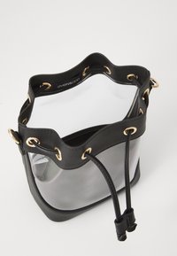 Zwarte leren emmer bag met doorzichtige plastic zijkanten, gouden oogjes en trekkoordsluiting. Voorzien van een zachte, gegolfde bovenrand en logo aan de binnenkant.