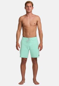 Shorts de bain vert menthe avec une taille élastique, fermeture à cordon de serrage et poches latérales. Fabriqués en matériau léger et à séchage rapide.