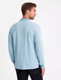 Polo a maniche lunghe azzurro chiaro con colletto, che presenta dettagli a contrasto nei polsini e nell'orlo. Tessuto morbido con una finitura strutturata.