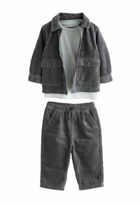 Grijze corduroyjas met knoopzakken, gecombineerd met een lichtgrijs shirt en bijpassende grijze corduroypantalon. Textuurstof overal.