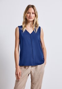 Top sin mangas de color navy con escote en V y costuras decorativas en el centro. Hecho de una tela suave, con un corte relajado y un ligero drapeado.