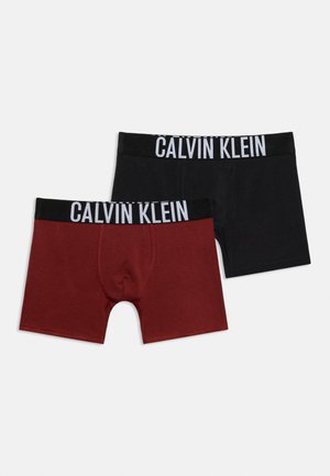 Kaks paari Calvin Kleini bokserpükse, üks must ja üks tumesinine, kummalgi must vöökoht ja valge logo tekst.