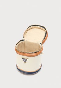 Στρογγυλή τσάντα σε κρεμ απόχρωση με καφέ και μπλε λεπτομέρειες, χρυσλό φερμουάρ και πλακέτα με λογότυπο. Το εσωτερικό διαθέτει επένδυση σε μπεζ με μοτίβο.