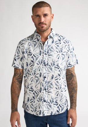 Chemise à manches courtes à boutons avec un motif de feuilles blanc et bleu marine, confectionnée en tissu léger, dotée d'un col et de boutons sur le devant.