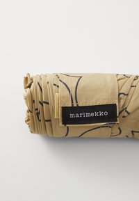 Tissu beige plié avec un motif floral noir, maintenu par une étiquette avec "marimekko" en texte blanc sur fond noir.