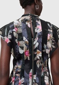 Blumen Kleid mit schwarzem Hintergrund, das rosa und weiße Orchideen zeigt, kurze Ärmel hat und einen Reißverschluss auf der Rückseite zum Schließen bietet.