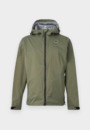 Kapucar olivno zelene barve iz vodoodpornega materiala z zadrgo spredaj, nastavljivimi zapestnimi trakovi in majhnim logotipom na levi strani prsnega koša, na enobarvnem ozadju.