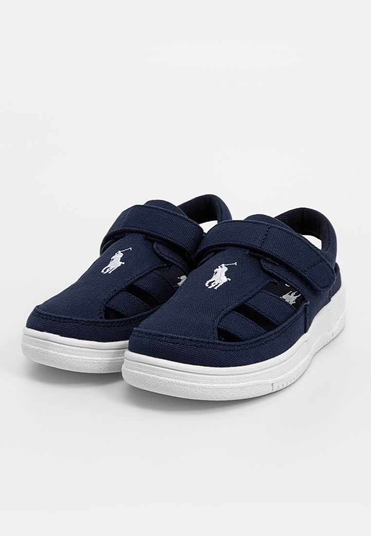 Chaussures en toile bleu marine avec une semelle blanche, dotées de sangles élastiques et d'un logo brodé à l'avant. Design ouvert pour une meilleure respirabilité.