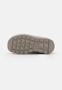 Grå sneaker såle med teksturert gummi for grep, med synlige dekkmønstre og merkevare preget på siden.