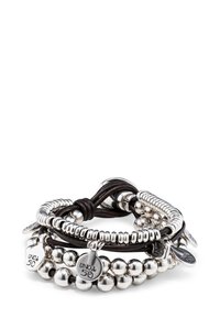 Esferas de metal plateado y tiras de cuero texturizado se entrelazan en una pulsera de múltiples capas, que presenta etiquetas de metal grabadas con "UNO de 50."