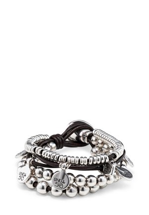 Esferas de metal plateado y tiras de cuero texturizado se entrelazan en una pulsera de múltiples capas, que presenta etiquetas de metal grabadas con "UNO de 50."
