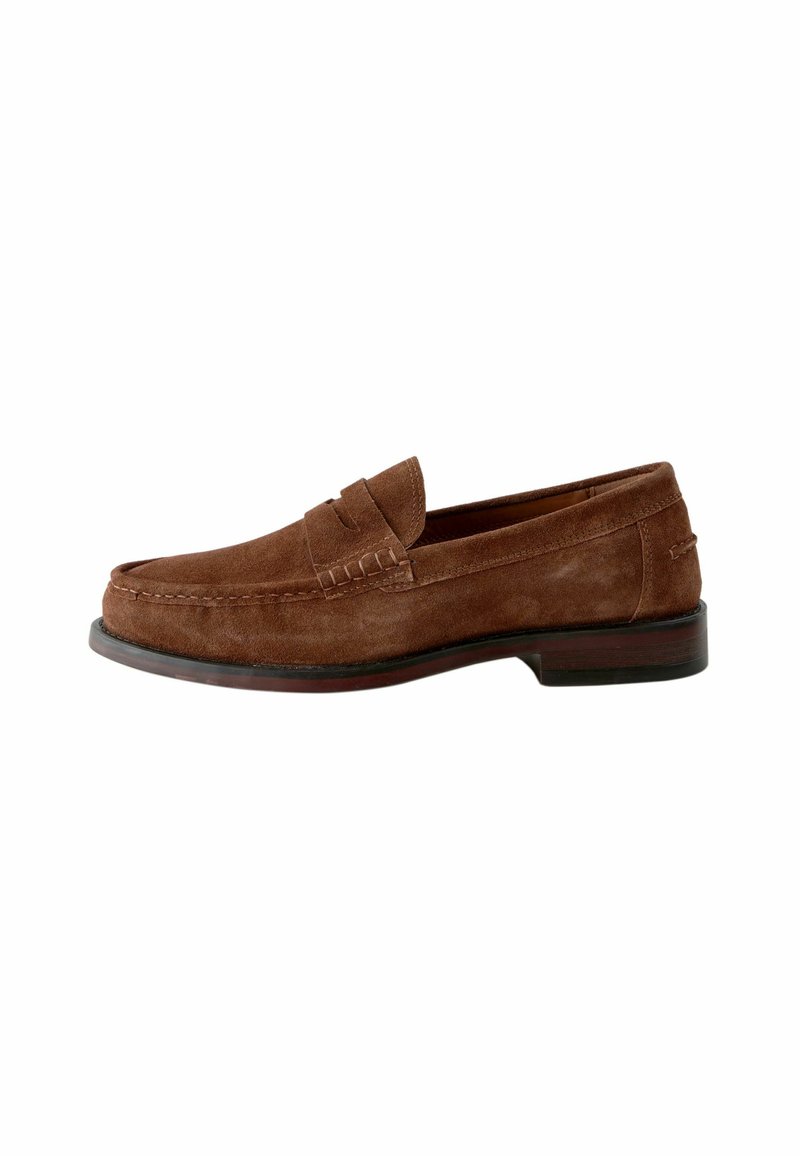 Mocasines de ante marrón con punta redonda, costuras decorativas y suela de cuero plana. Presenta un diseño clásico sin cordones.