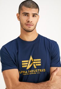 Navyblaue Baumwoll-T-Shirts mit einem goldenen Logo- und Textdruck. Klassisches Rundhalsdesign mit kurzen Ärmeln und weichem Material.