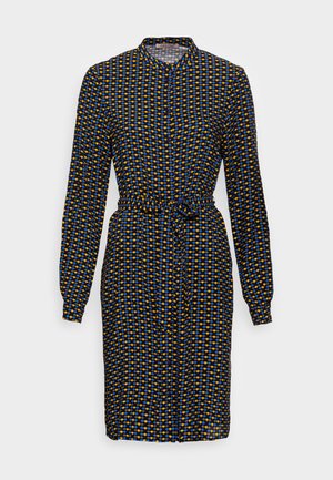 Robe boutonnée à manches longues avec col, ceinture à la taille et motif géométrique bleu, jaune et noir sur fond sombre.