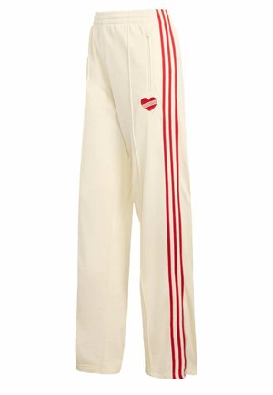 Cream-colored sweatpants with red stripes down the sides, featuring a red heart logo on the left thigh and a side zip pocket.