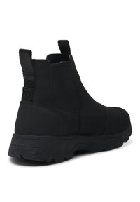 Botas Chelsea negras hechas de tejido texturizado con suela de goma plana. Cuentan con tiradores y una construcción impermeable para mayor durabilidad.