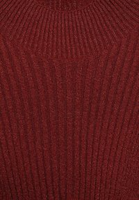 Lähikuva tummanpunaisesta ribbikutoisesta kankaasta, jossa on hienovarainen kiilto ja näkyvät pystysuuntaiset sekä kulmaiset tekstuurikuviot.