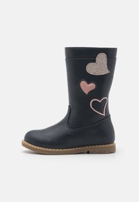 Botte imperméable bleu marine avec une texture lisse, ornée d'appliqués en forme de cœur roses et pailletés. Semelle marron texturée avec des détails de couture.