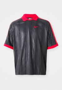 Black short-sleeve polo shirt with red collar and cuffs, subtle vertical stripes with "Nike" text, and red Nike swoosh logo on chest.