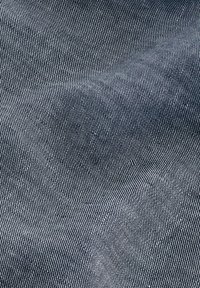 Tissu en denim à tissage serré, affichant une couleur bleu foncé avec de légères rayures grises, une texture lisse et un éclat minimal.
