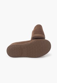 Scarpe slip-on in suede marrone con suola in gomma testurizzata, caratterizzate da un design semplice e punta curva. La suola presenta un motivo ondulato.