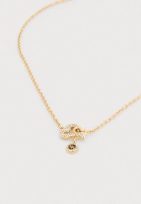 Χρυσή αλυσίδα με μενταγιόν σε σχήμα καρδιάς διακοσμημένο με διαφανείς στρας και στρογγυλό φυλαχτό με διακοσμητικό σχέδιο.