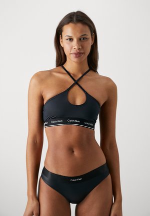 Set di bikini nero con top incrociato caratterizzato da un design a chiave e banda elastica con dettaglio del logo; texture liscia e stile minimalista.