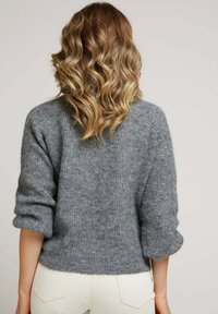 Pull en tricot gris au fit décontracté, avec des manches trois-quarts et une texture douce. Détails côtelés près de l'ourlet et des poignets.