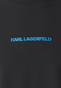 Čierne tričko s vyvýšeným modrým nápisom "KARL LAGERFELD." Dizajn kladie dôraz na jednoduchý, moderný vzhľad s okrúhlym výstrihom.