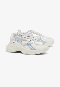 Le sneaker Lacoste presentano una tomaia in mesh bianco e materiale sintetico con dettagli argento e blu, una suola texturizzata e chiusura con lacci.