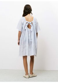 Blauwe en witte gestreepte jurk met korte mouwen, open rug en strikdetail; heeft delicate borduursels nabij de zoom.