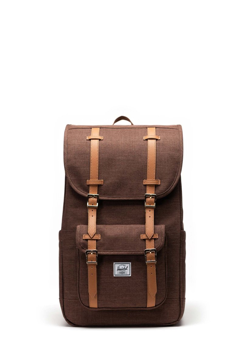 Brun tygryggsäck med en strukturerad form, som har läderremmar, metallspännen, framficka och en design med topplock.