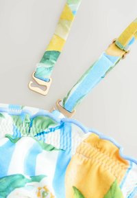 Multikleurige bikini-top met blauwe, groene en gele bloemenpatronen, met verstelbare bandjes en gouden hardwareaccenten. Getextureerde stof.