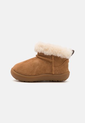 Brauner Wildleder-Stiefel mit cremefarbenem flauschigem Lammfell-Bündchen und Gummisohle, entworfen für Wärme und Komfort.