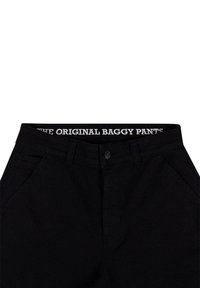 Black baggy jeans featuring a button closure and side pockets, with a waistband labeled “THE ORIGINAL BAGGY PANTS” in white text.