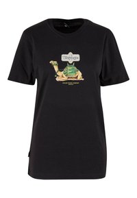 Sort bomulds T-shirt med et farverigt kamel-grafik, der har en sadel og blomsterdesign, ledsaget af teksten "Voyage" og "Cayler Travel Company".