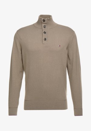 Beżowy sweter z dzianiny z długim rękawem, z prążkowanym wysokim kołnierzem, patką na guziki z czterema guzikami, małym logo na piersi oraz prążkowanymi mankietami i dolnym brzegiem.