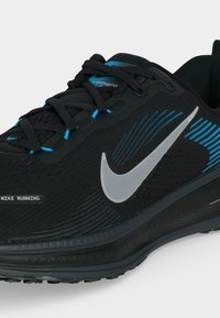 Μαύρο αθλητικό παπούτσι Nike για τρέξιμο με γκρι σήμα, μπλε λεπτομέρειες και μαύρα κορδόνια σε λευκό φόντο.