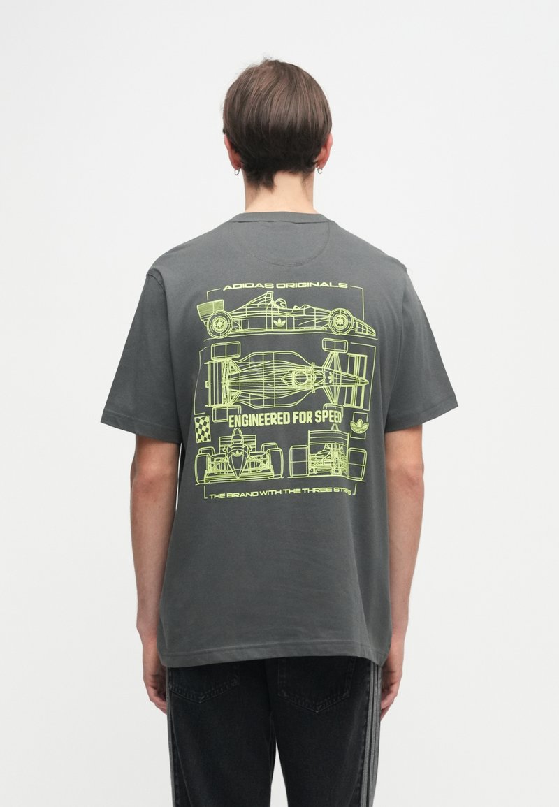 Grijze katoenen t-shirt met een neongele grafiek van raceauto-ontwerpen en de tekst "Engineered for Speed" op de achterkant. Korte mouwen, ronde hals.
