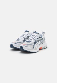 Weiße Sportschuhe mit marineblauen und orangenen Akzenten. Obermaterial aus Mesh mit strukturierten Overlays, flachen Schnürsenkeln und Gummisohle für besseren Halt.
