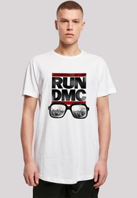 White cotton t-shirt featuring a graphic print with "RUN DMC" text and sunglasses reflecting a cityscape design. Short sleeves, relaxed fit.