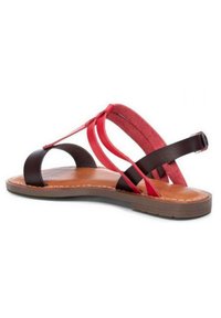Sandalo marrone e rosso con suola piatta. Presenta cinturini incrociati in textures opache e scamosciate, con una cintura alla caviglia regolabile.