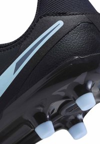 Czarne korki piłkarskie z teksturowaną cholewką, niebieskimi akcentami i formowaną podeszwą z stożkowymi kołkami zapewniającymi przyczepność.