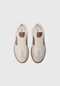 Baltos sportinės bateliai su rudomis akcentais ir raštuotomis šoninėmis plokštėmis. Pagaminti iš odos ir tekstūruotos zomšos, turi apvalią nosį ir plokščiu padu.