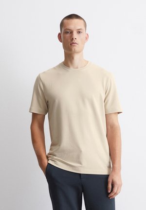 Beige T-Shirt mit kurzen Ärmeln und Rundhalsausschnitt, aus weichem Stoff gefertigt. Verfügt über eine lässige Passform und dezente Markenkennzeichnung am unteren Saum.