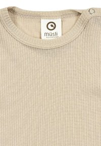 Béžová žebrovaná bavlněná košile s kulatým výstřihem, která má patentek na jednom rameni a štítek s nápisem "müsli."