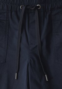 Pantalones cortos azul marino con cinturilla elástica, cierre de cordón y dos bolsillos laterales. Tejido suave con costuras visibles y detalles metálicos.