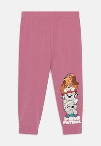 Pantalon de survêtement rose en tissu doux. Présente un graphique de chiens de dessin animé empilés les uns sur les autres avec le texte "PAW PATROL" en bas.