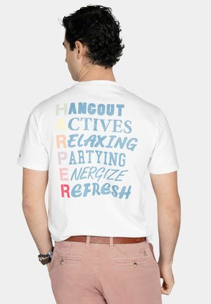 Hombre con camiseta blanca con texto colorido en la espalda: "SALIR, ACTIVIDADES, RELAJARSE, FIESTA, ENERGIZARSE, REFRESCARSE."